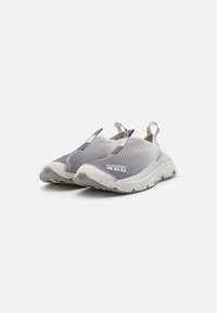 Szürke hálós sneaker, ami slip-on dizájnnal készült, fehér részletekkel és gumitalppal. Kiemelkedő húzófülek az egyszerű felvétel érdekében.