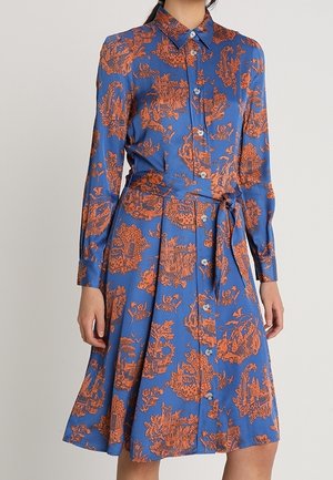 Robe bleue à motifs avec manches longues, fermeture à boutons sur le devant, et ceinture à nouer à la taille. Présente des motifs floraux orange et des paysages. Texture lisse.