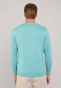 Turkusowy sweter z długim rękawem, z prążkowanymi mankietami i dołem. Dzianinowa tekstura z okrągłym dekoltem i małym logiem umieszczonym z boku.