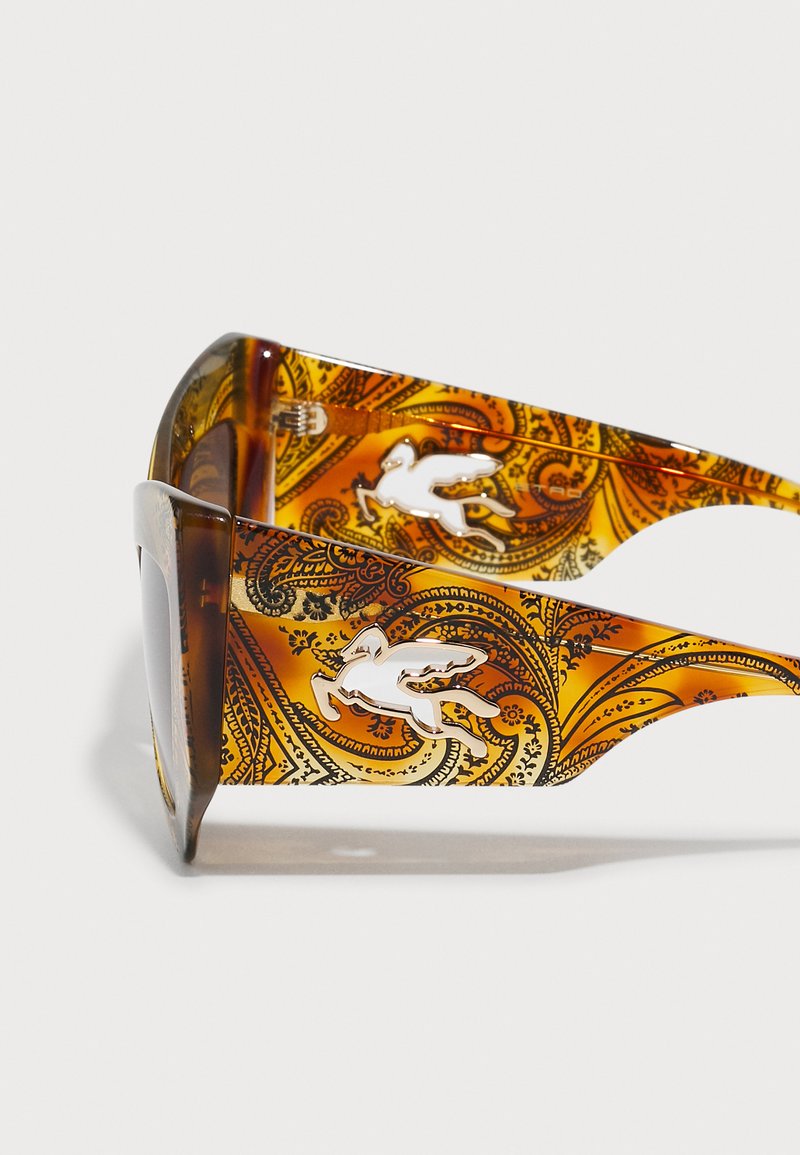 Brązowe przeciwsłoneczne okulary w odważny wzór paisley, z białym emblematem na zausznikach oraz eleganckim, kanciastym kształtem oprawki.