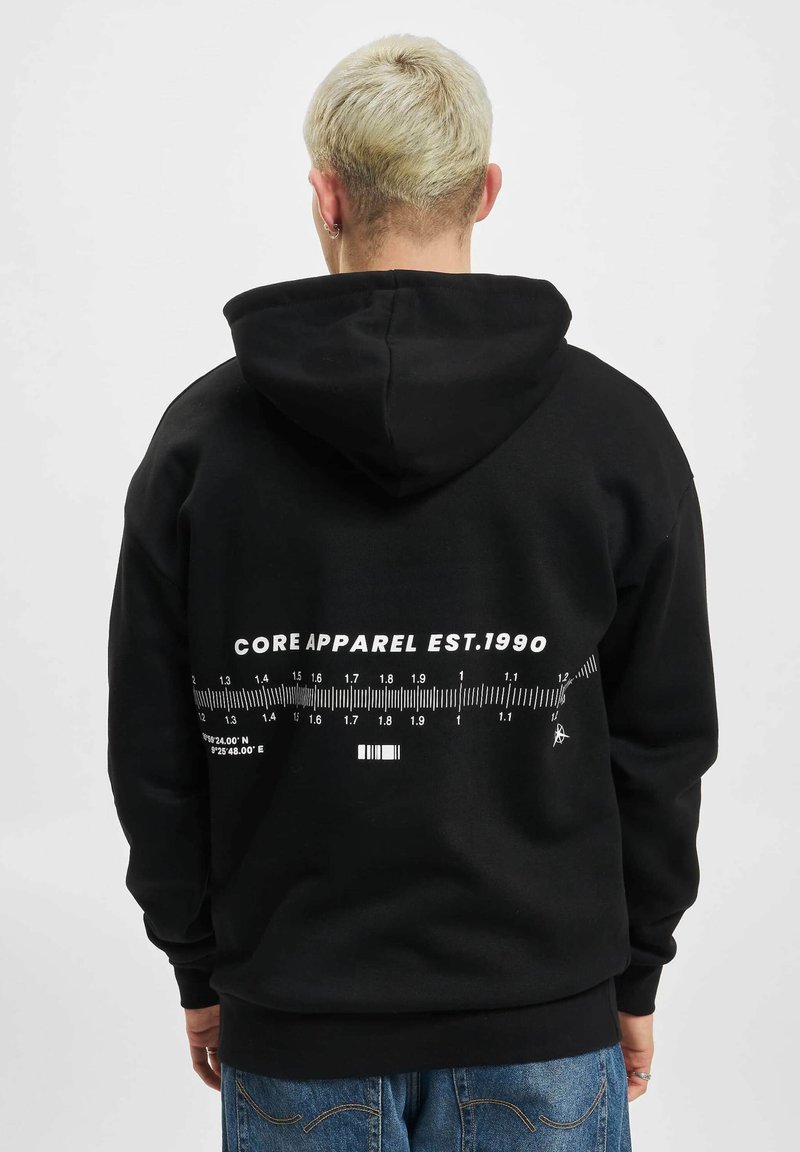 Svart hettegenser laget av en bomullsblanding, med et stort hvitt grafisk trykk av et linjal og teksten "CORE APPAREL EST.1990" på baksiden.