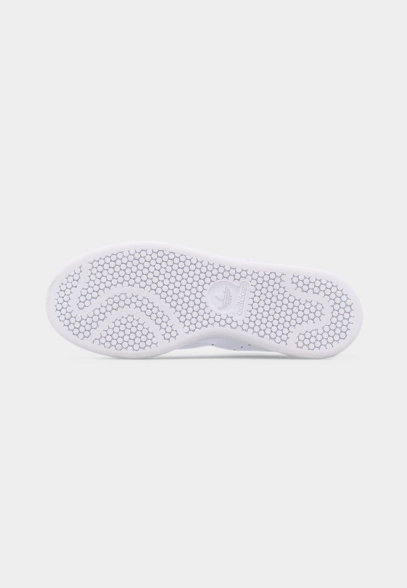 Hvid sneakersål med sekskantet mønster og Adidas-logo præget i midten mod en ensfarvet lys grå baggrund.