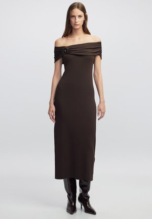 Braunes, schulterfreies, geripptes Kleid mit gerafften Details und einem dekorativen Knopf. Langer, taillierter Schnitt, kombiniert mit kniehohen Stiefeln.