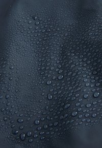 Vodotesná tkanina s textúrovaným povrchom v tmavomodrej farbe, s množstvom kvapiek vody, ktoré vytvárajú lesklý, odrazov ý efekt.