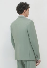 Giacca di abito verde chiaro realizzata in tessuto testurizzato, con vestibilità slim, spacco singolo e polsini a quattro bottoni. Design del colletto semplice.