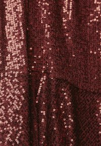 Burgundy tyg täckt med rosaguldiga paljetter; har en texturerad yta med varierande storlekar på paljetterna för en glittrande effekt.