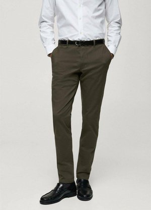 Olivi vihreät, slim-fit-housut vyölenkeillä, sivutaskuilla ja sileällä pinnalla, yhdistettynä mustiin juhlakenkihin ja valkoiseen nappikaulukseen.