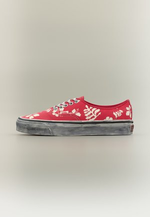 Rød Vans-sneaker med hvidt blomstermønster, grå snørebånd og slidt sort sål, set fra siden på en enkel neutral baggrund.
