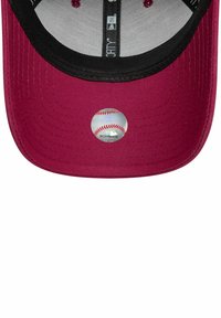 Cappello da baseball color marsala con visiera piatta, sottovisiera nera e un'etichetta circolare con una grafica di baseball. Tessuto testurizzato con cuciture visibili.