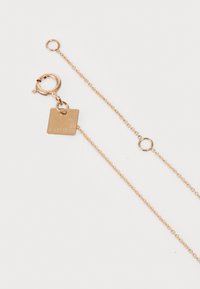 Collana in oro rosa 18 carati con una piccola targhetta quadrata. Presenta un moschettone e anelli uniformi, evidenziando una texture lucida.