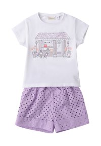 Camisa blanca de manga corta con una ilustración de una pastelería, combinada con pantalones cortos lavanda que presentan lunares texturizados y puños doblados.