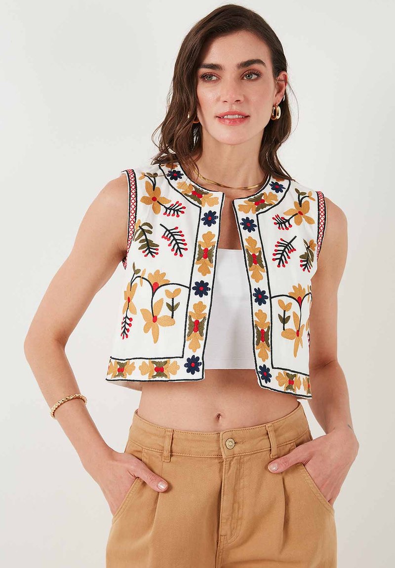 Embroidered vest in white fabric featuring floral patterns in orange, blue, and green, with a round neckline and cropped design.