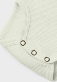 Bodysuit en tissu côtelé vert clair présentant trois boutons-pression en métal et une finition douce et texturée. Coutures lisses le long des bords.