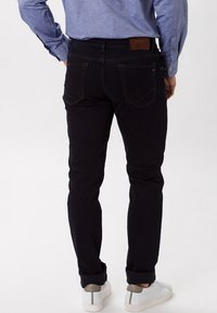 Mörkblå jeans med slim fit, med bakfickor och sydda detaljer. Matching med vita sneakers och en ljusblå skjorta.