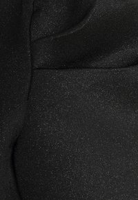 Tissu noir avec une texture subtilement scintillante, surface lisse et couleur uniforme, présentant une vue en gros plan du motif de tissage du matériau.