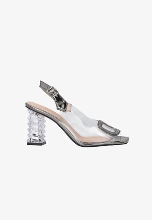 Durchsichtiger Kunststoff-Slingback-Schuh mit einem durchsichtigen, gestapelten Absatz, silbernen Akzenten und einem offenen Zehenbereich, der mit einer dekorativen Schnalle verziert ist.