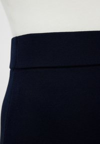 Navy sininen ribbitetty kangas vyötärönauha, jossa on sileä pinta; ylhäällä on litteä sauma ja alla teksturoitu pinta.