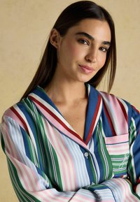 Striped pajama set featuring pastel colors, including pink, blue, green, and red; soft fabric with a notched collar and front pocket detail.