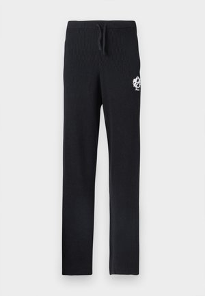 Schwarze Strickhose mit geripptem Muster, versehen mit einem weißen Logodetail am oberen Bein und einem Kordelzugbund.