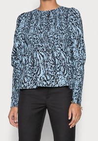 Blusa blu e nera con motivo a lungo maniche, corpino arricciato e polsini elasticizzati. Il tessuto presenta disegni astratti floreali e di animali.