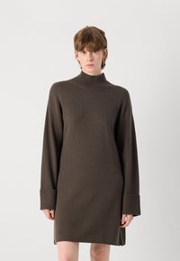 Καφέ πλεκτό φόρεμα με ψηλό λαιμό, μακριά μανίκια και ριμπ μανσέτες. Έχει άνετη εφαρμογή και ομαλή υφή.