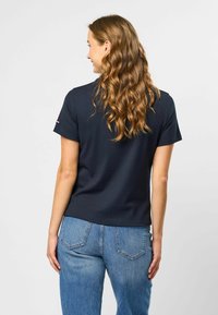 Navy ribbet t-skjorte med kort erm og runde halsutskjæring, pyntet med en liten logo på ermene, kombinert med høyt liv blå denim jeans.