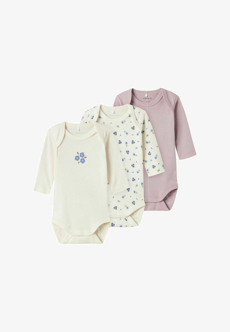 Trois bodies à manches longues pour bébé dans une couleur crème avec des imprimés floraux, un motif ivoire et un lavande uni, fabriqués en tissu doux.