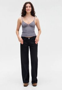 Gray striped crop top with thin straps paired with black wide-leg jeans featuring a button front and front pockets. Solid brown footwear.