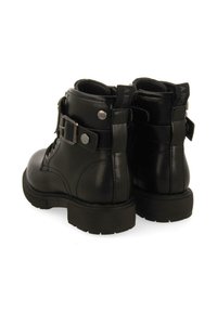 Botas de tobillo de cuero negro con un acabado texturizado, que presentan un hebilla lateral, puntera redonda y suela de goma. Incluyen una pestaña para facilitar su puesta.