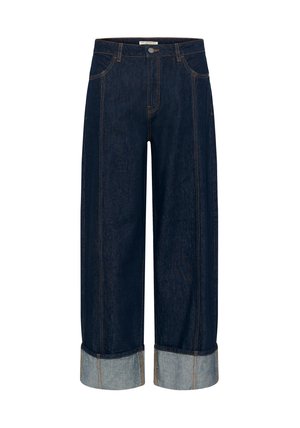 Jean en denim foncé à jambe large avec un lavage moyen, revers pliés et surpiqûres dorées contrastantes soulignant les poches et les coutures.
