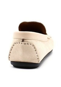 Pantoufle en suède beige avec un dos arrondi, semelle en caoutchouc noir et détail de couture visible le long des bords. Design simple et à coupes basses.