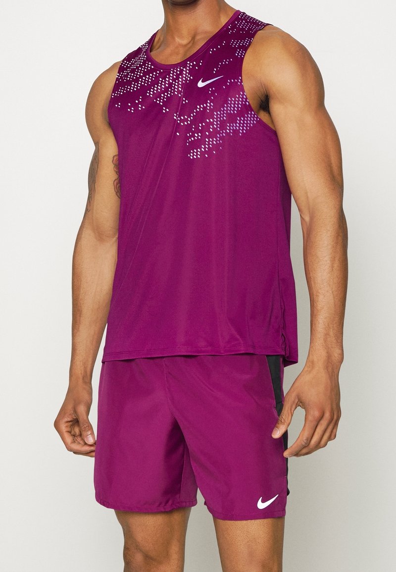 Lila sporttopp med ett prickigt mönster vid halsringningen, i kombination med matchande shorts. Har en vit Nike-logotyp på bröstet.