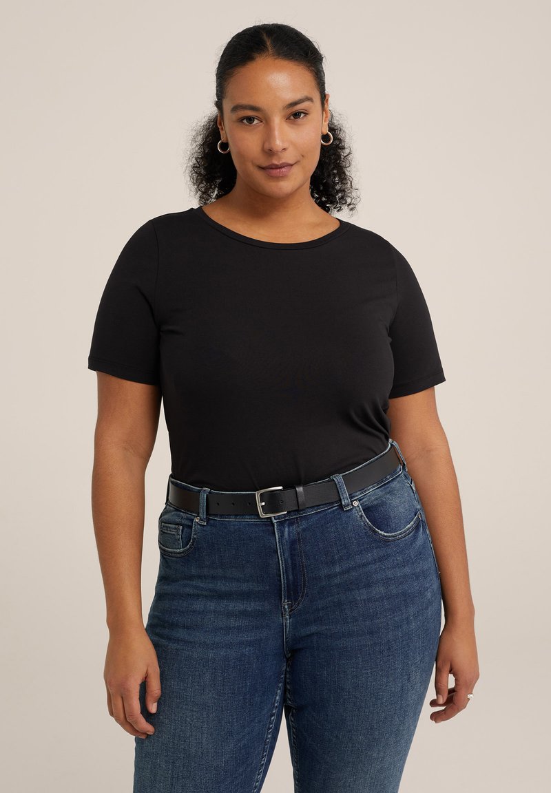 Melnas īsām piedurknēm T-krekls pieguļošā stilā, apvienots ar ziliem džinsiem un melnu jostu. Audums izskatās gluds un viegls.