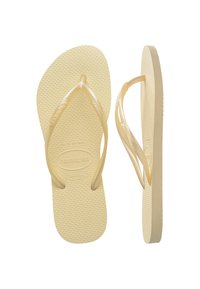Gule flip-flops laget av gummi med en teksturert fotseng og glatte, fleksible stropper. Har en logo på innersålen.