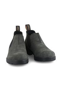 Botas de cuero gris hasta el tobillo con paneles laterales elásticos, punta redondeada y suela de goma negra; presenta una tira de agarre con el logotipo en la parte posterior.
