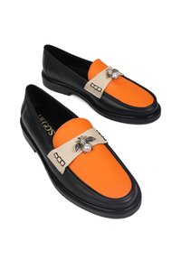 Czarne loafersy z pomarańczowymi i beżowymi akcentami, z ozdobnym pszczołem z perłą, gładka skórzana tekstura i niski profil.