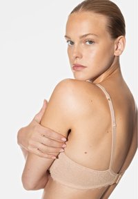 Soutien-gorge en dentelle nude, avec des bretelles réglables, un délicat motif floral et une fermeture à crochet. Texture douce, design minimaliste.