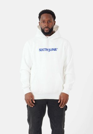 Witte hoodie met de tekst "SIXTH JUNE" in blauwe letters over de borst. Bevat een buidelzak en een verstelbare trekkoordkap. Zwarte broek draagt.