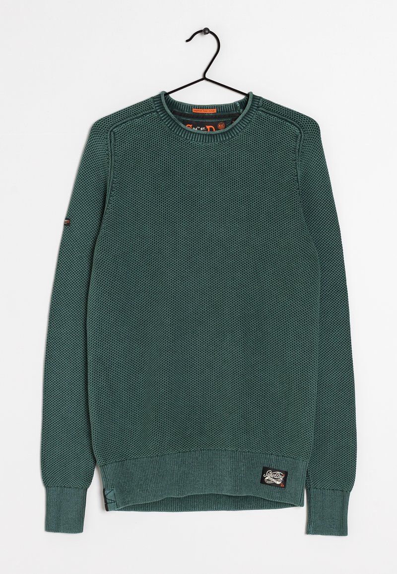 Pull en tricot vert avec un motif texturé, col rond, poignets et ourlet côtelés, comportant une étiquette sur le bas à gauche.
