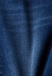 Tela de mezclilla azul oscuro con textura suave, que presenta patrones de tejido diagonal y un desvanecimiento sutil. Sin elementos metálicos ni detalles visibles.