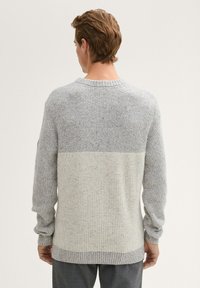 Hellgrauer Strickpullover mit einem melierten Muster, ausgestattet mit einem kontrastierenden cremerfarbenen horizontalen Band am unteren Saum und Rippstrickbündchen.