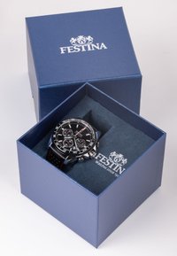 Orologio cronografo nero con accenti argentati in una scatola blu. L'orologio ha un cinturino in gomma testurizzata e un quadrante nero con indicatori bianchi.
