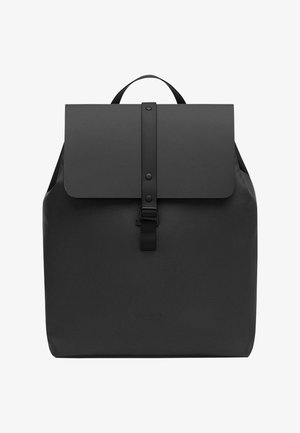 Crna ruksak izrađena od glatkog, vodootpornog materijala. Ima preklopno zatvaranje s trakom i kopčom, te jedan gornji rukohvat za nošenje.