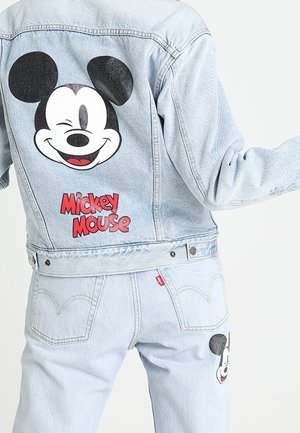 Veste en jean bleu clair et jeans avec un grand visage de Mickey Mouse faisant un clin d'œil et texte rouge "Mickey Mouse" au dos de la veste.