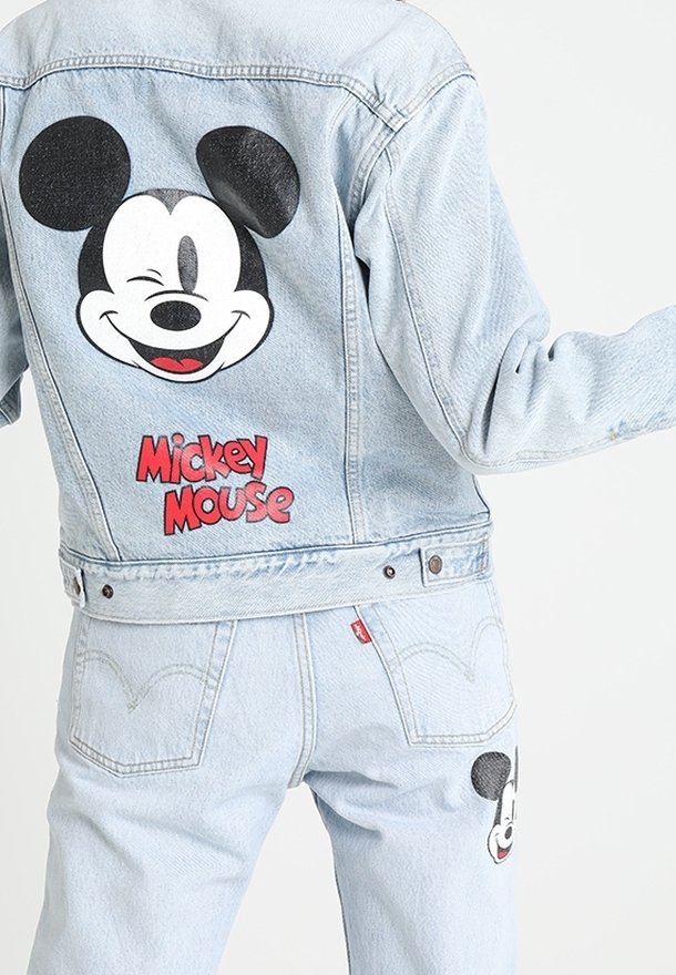 Veste en jean bleu clair et jeans avec un grand visage de Mickey Mouse faisant un clin d'œil et texte rouge "Mickey Mouse" au dos de la veste.