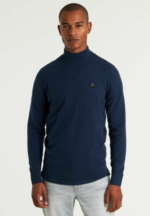 Maglione a collo alto blu navy realizzato in un tessuto a maglia liscia, con un piccolo logo nero sul petto e polsini e orlo a coste.
