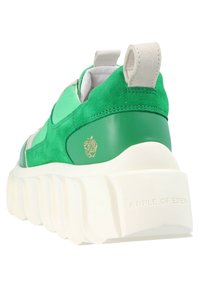 Gröna sneakers med en blandning av mocka och slät läder, tjock vit sula och en logotyp vid hälen. Kontrasterande texturer synliga.