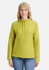 Sweter w kolorze limonkowym, żebrowany, z wysokim kołnierzem i regulowanym trokiem. Posiada długie rękawy oraz haft "SCOSY" na dolnym brzegu.
