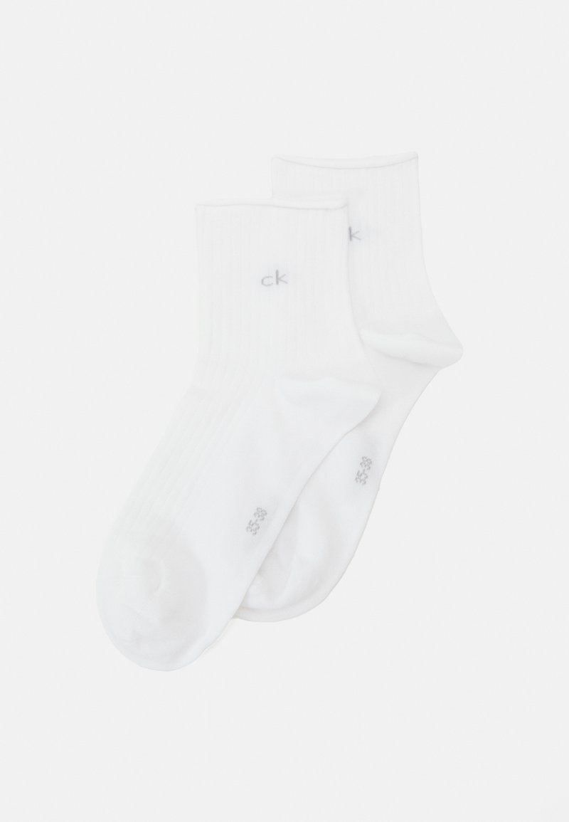 Chaussettes blanches en coton de type crew avec une texture côtelée et un petit logo "ck" gris sur le côté. Bout arrondi et bord élastiqué pour un bon ajustement.
