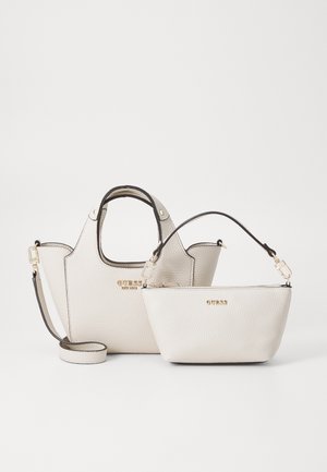 Zwei Guess-Handtaschen aus strukturiertem weißen synthetischen Material. Die größere Tasche verfügt über zwei Griffe, während die kleinere einen abnehmbaren Schulterriemen hat. Goldene Akzente sind sichtbar.